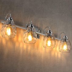 three lights are attached to the side of a wall mounted light fixture with clear glass shades