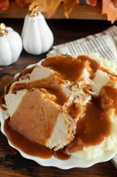 a white plate topped with mashed potatoes covered in gravy next to pumpkins