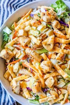 a white bowl filled with chicken and pasta salad on top of a blue striped table cloth