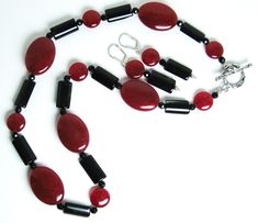 Red mountain jade, black tourmaline necklace (19 inches) with a sterling silver toggle clasp. The matching earrings are on sterling silver leverbacks with a 1.4-inch drop. Red mountain jade is a gemstone of color-enhanced high-grade dolomite marble from Asia. Both red mountain jade and tourmaline are gemstones. There are two shapes of red mountain jade beads: flattened ovals (25 x 18 mm) and flattened round beads (11 mm in diameter).The black tourmaline beads are flattened cylinders (16 x 9 mm).There are also 4 mm black faceted beads in the necklace. Red mountain jade is the gemstone of October-November. Tourmaline is a birthstone of October. Jade Gemstone Jewelry Gift, Jade Gemstone Jewelry For Gifts, Elegant Jade Jewelry Gift, Adjustable Red Formal Jewelry, Elegant Formal Jade Jewelry, Fine Jewelry Jade Pendant, Fine Jade Pendant Jewelry, Classic Jade Jewelry As Gift, Classic Jade Jewelry For Gift