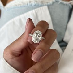 a woman's hand holding a diamond ring in front of her face and the other hand