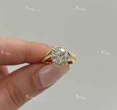 a woman's hand holding a yellow gold ring with a diamond in the middle