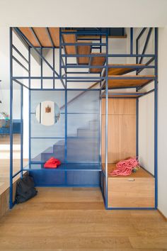 a room with some stairs and a blue cage on the wall next to wooden flooring