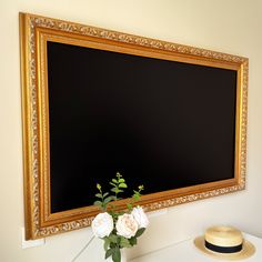 there is a vase with white flowers in front of a blackboard on the wall