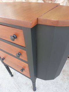 a brown and black dresser sitting on top of a white floor