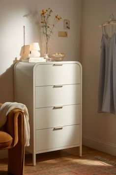 a white chest of drawers sitting next to a chair