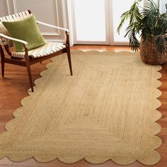 a large rug with scalloped edges on a wooden floor next to a chair and potted plant