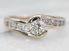 an engagement ring with two diamonds on the side and one diamond in the middle, sitting on a white surface