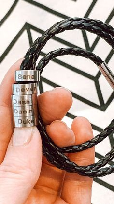 a person holding a black leather bracelet with two metal padlocks