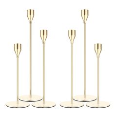 three gold metal candlesticks on white bases