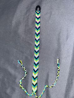 an anchor made out of knitted material on a gray background with blue, green and white stripes