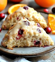 two scones on a plate with oranges and cranberries around the edges