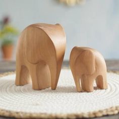 two wooden elephants standing on top of a rug