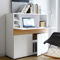 a laptop computer sitting on top of a white desk next to a book shelf filled with books