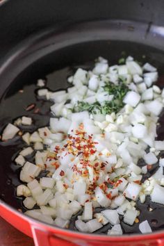 onions and herbs are being cooked in a pan