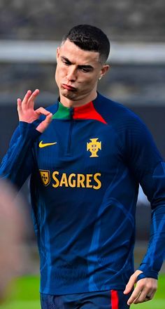 a soccer player is holding his hand up to the sideline and making a gesture