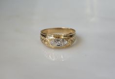 a yellow gold ring with two diamonds on it's sides, sitting on a white surface