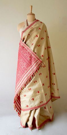 "This is hundred percent authentic Muga Silk Saree . It has Muga silk in the warp and weft . The interwoven motif yarns are in Guna ( golden zari ) and Acrylic. The design is traditional and known as Gamkharu and one of the most iconic designs of the region. The red and Muga combination is the classic combination that was always part of the bridal trousseau. Muga Silk - The most valued silk from India. Almost exclusively reared and produced in Assam, India. It is indigenous to the Brahmaputra Va Bohemian Traditional Wear With Weaving Work For Festivals, Beige Traditional Shawl With Traditional Patterns, Traditional Shawl With Woven Motifs For Ceremonies, Folk Style Dupatta With Traditional Drape And Motifs, Folk Style Handloom Dupatta For Festivals, Traditional Drape Handloom Shawl For Wedding, Traditional Draped Embroidered Fabric For Festivals, Handloom Shawl For Wedding With Traditional Drape, Wedding Shawl In Traditional Drape Handloom