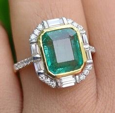 an emerald and diamond ring on someone's finger