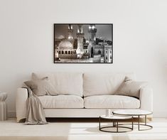 a living room with a white couch and coffee table in front of a wall mounted black and white photograph