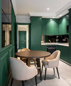 a kitchen with green cabinets and white chairs around a round wooden table in the center