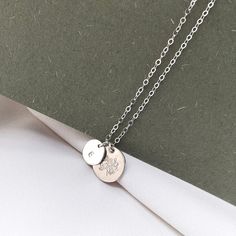 "A sterling silver birth flower necklace that you can personalise! Choose your birth flower on one disc and an initial for the second one. The tiny initial disc pendant sits beside the larger flower one and they hang from a fine sterling silver chain. Each birth flower necklace comes with an elegant card, featuring a vintage illustration and details about what the flower represents. A subtle botanical piece of jewellery, inspired by a love of nature. DIMENSIONS: Pendant: 12mm. Chain: 16-18\" / 4 Silver Dainty Name Necklace With Birthstone, Sterling Silver Charm Necklaces For Mother's Day, Delicate Silver Initial Pendant Name Necklace, Delicate Silver Initial Pendant Necklace, Dainty Silver Initial Necklace For Personalized Gift, Delicate Silver Initials Name Necklace, Delicate Silver Initial Necklace For Anniversary, Dainty Silver Initial Necklace With Charms, Silver Initial Pendant Necklace For Her