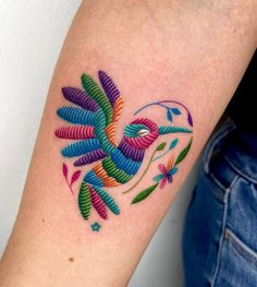 a colorful bird tattoo on the arm