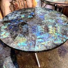 a table that has some kind of blue and purple design on it with two chairs in the background