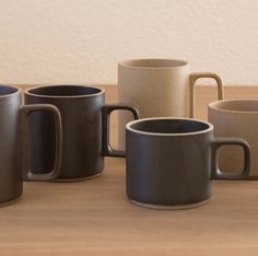 five coffee mugs sitting on top of a wooden table next to eachother