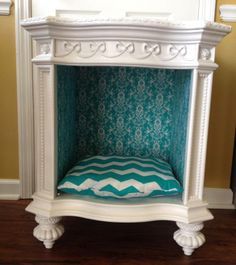 a dog bed made out of an old fireplace with a blue and white pillow on it