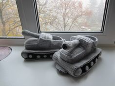 two knitted toy tanks sitting on top of a window sill