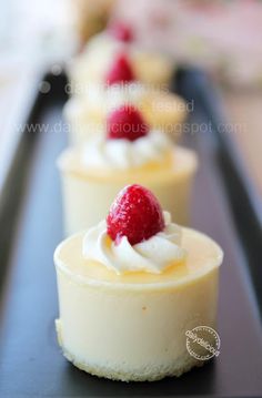 three small desserts with whipped cream and strawberries on top are lined up in rows