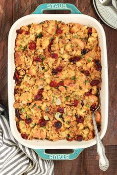 a casserole dish filled with stuffing and cranberries on a wooden table