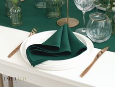 a white plate topped with green napkins on top of a table next to silverware