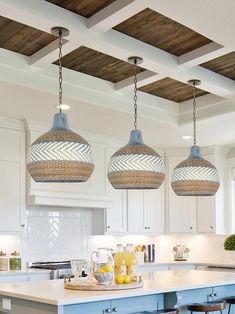 three lights hanging from the ceiling above a kitchen island with stools in front of it