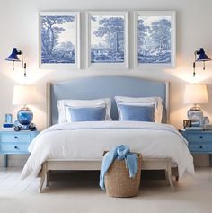 a blue and white bedroom with two pictures on the wall