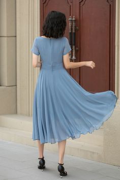 a woman in a blue dress is standing by a door with her back to the camera