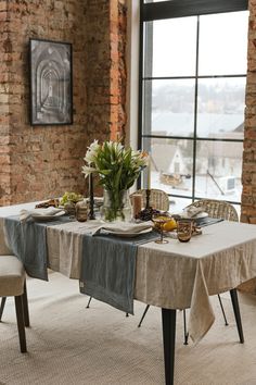 a dining room table with two chairs and a vase filled with flowers