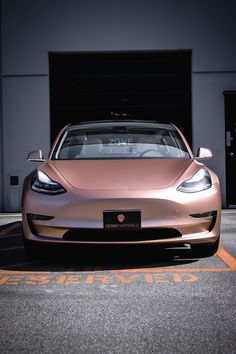 an electric car is parked in front of a garage with the door open and it's lights on