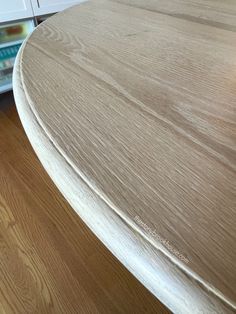 a close up view of a wooden table with white drawers in the backgroud