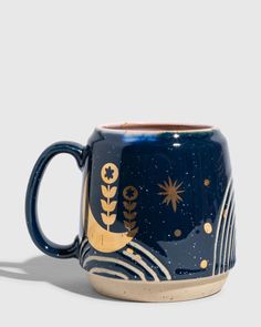 a blue and gold coffee mug with stars and moon designs on the outside, sitting against a white background