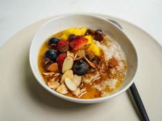 a bowl of oatmeal with fruit and nuts in it on a plate