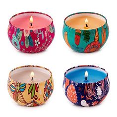 four different colored candles in bowls with designs on them and one candle lit inside the bowl