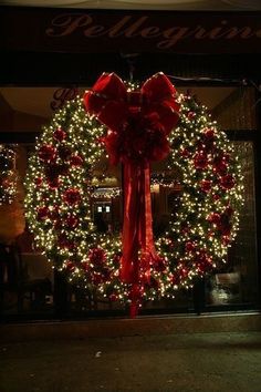 a christmas wreath with red bows and lights in the background, is lit up at night