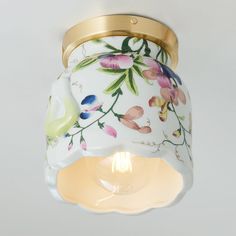 the light fixture is decorated with flowers and gold trimmings, as well as a glass shade