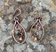 Hammered Copper with copper figure eights and flame colored crystal dangles. Come on handmade copper ear wires.Approximately 2" long from the top of the ear wire and 13/16" wideThese Earrings have been antiqued, polished and sealed.Sealed with Protectaclear ProtectaClear is a clear, protective coating that is tough enough to protect jewelry and is safe for wear against skin. ProtectaClear is practically invisible once applied and will seal and protect jewelry from tarnish, oxidation, and corrosi Colored Wire Jewelry, Bronze Teardrop Copper Earrings, Bronze Wire Wrapped Teardrop Earrings, Bronze Copper Teardrop Earrings, Copper Teardrop Dangle Earrings, Bronze Wire Wrapped Copper Earrings, Hand Forged Copper Wire Drop Earrings, Hand Forged Bronze Earrings With Copper Wire, Hammered Copper Jewelry