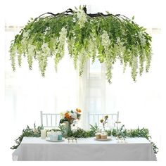 the table is covered with greenery and white flowers, including an orchid plant hanging over it