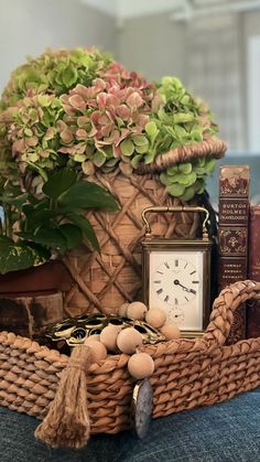 a wicker basket filled with books and a clock sitting on top of a table