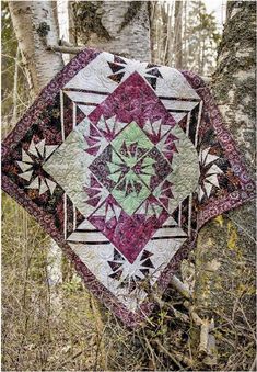 a quilt hanging from a tree in the woods