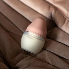 a baby bottle sitting on top of a brown blanket next to a pink and white object